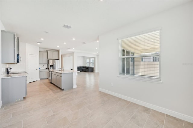 kitchen with gray cabinetry, open floor plan, light countertops, appliances with stainless steel finishes, and baseboards