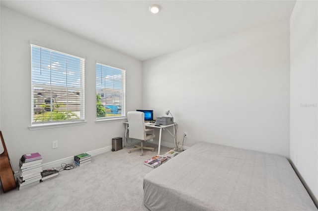 carpeted bedroom featuring baseboards and a desk