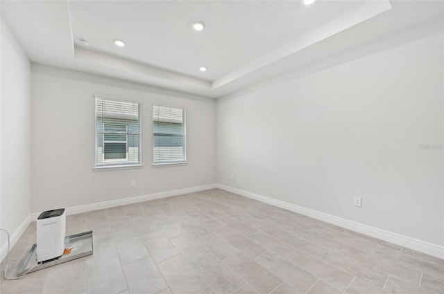 spare room with a tray ceiling, recessed lighting, baseboards, and a smoke detector