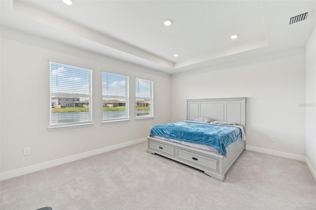 bedroom featuring light colored carpet, recessed lighting, baseboards, and a tray ceiling
