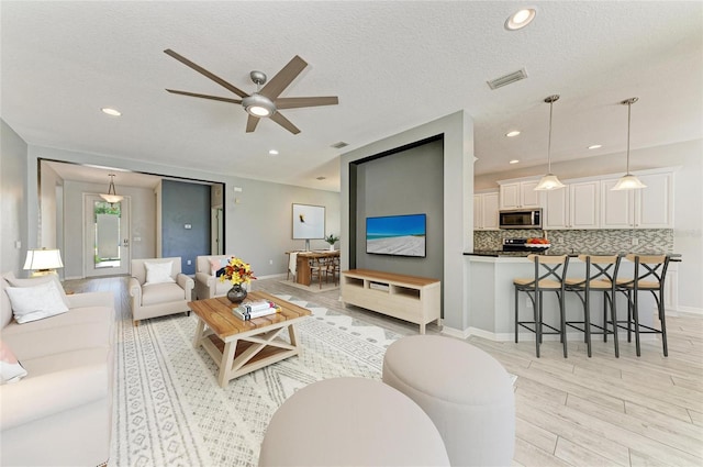 11811 Fennemore Way, Parrish, FL 34219 - living room featuring light wood-style floors, a ceiling fan, baseboards, recessed lighting, and a textured ceiling
