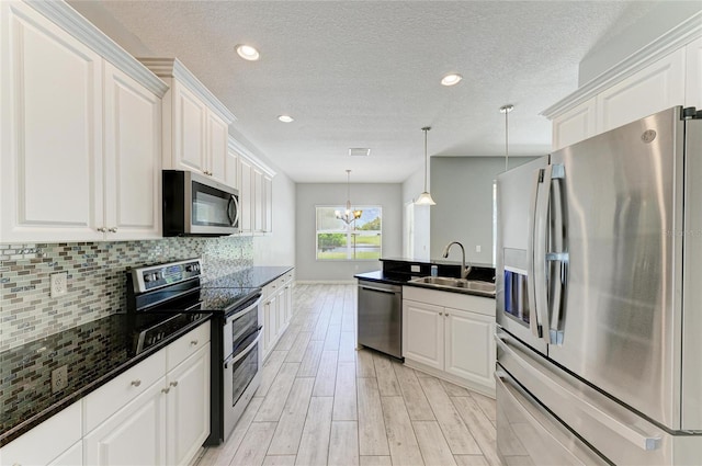 11811 Fennemore Way, Parrish, FL 34219 - kitchen featuring appliances with stainless steel finishes, a sink, white cabinets, tasteful backsplash, and a textured ceiling