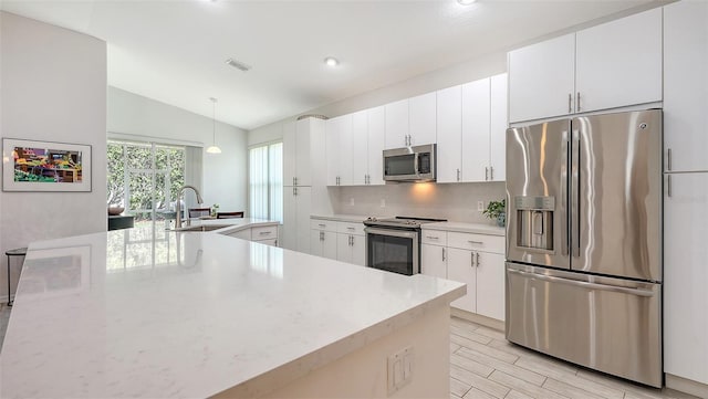 6721 Oak Manor Dr, Lakewood Ranch, FL 34202 - kitchen with stainless steel appliances, a sink, lofted ceiling, white cabinetry, and backsplash