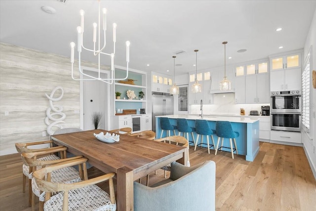 dining room featuring wine cooler, a chandelier, light wood-type flooring, and recessed lighting
