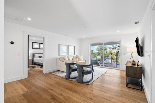 living area featuring light wood-type flooring, attic access, and recessed lighting