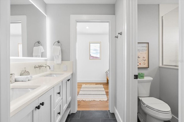 bathroom with toilet, double vanity, and tile patterned floors