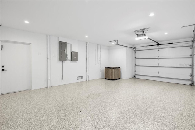garage featuring electric panel, recessed lighting, and a garage door opener