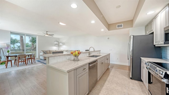 800 N Tamiami Trl Unit 317, Sarasota, FL 34236 - kitchen featuring a sink, appliances with stainless steel finishes, an island with sink, a ceiling fan, and backsplash