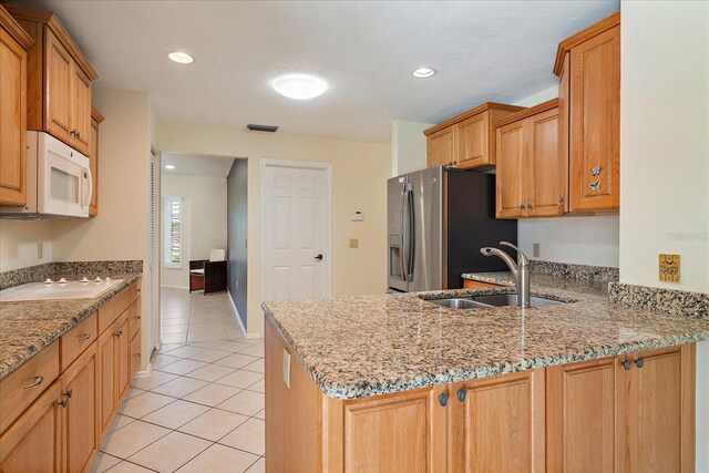 3335 Meadow Run Ter, Venice, FL 34293 - kitchen featuring a sink, white appliances, light tile patterned floors, a peninsula, and light stone counters