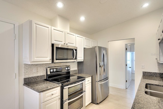 5812 Garden Lakes Fern, Bradenton, FL 34203 - kitchen featuring stainless steel appliances, white cabinetry, light wood-style floors, decorative backsplash, and a sink