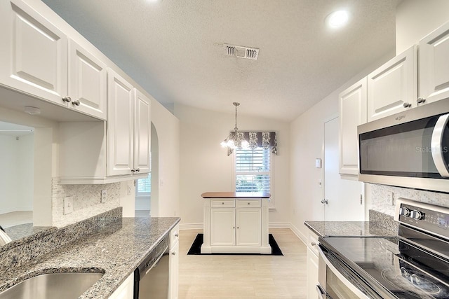 5812 Garden Lakes Fern, Bradenton, FL 34203 - kitchen with appliances with stainless steel finishes, decorative backsplash, light wood-style flooring, white cabinets, and a textured ceiling