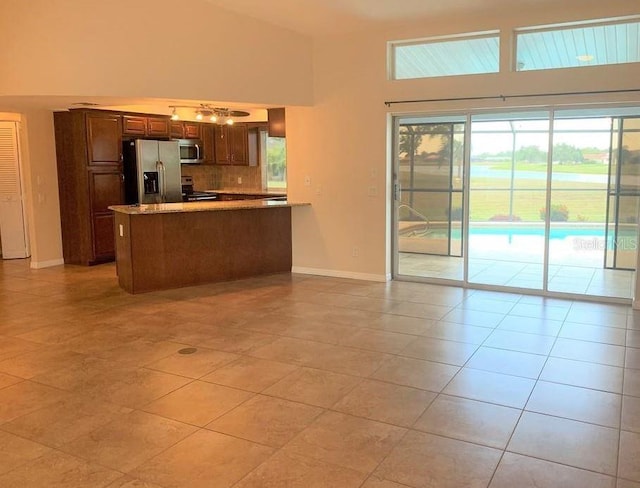 2178 Calcutta Rd, Punta Gorda, FL 33983 - kitchen featuring appliances with stainless steel finishes, plenty of natural light, baseboards, light tile patterned flooring, and a towering ceiling