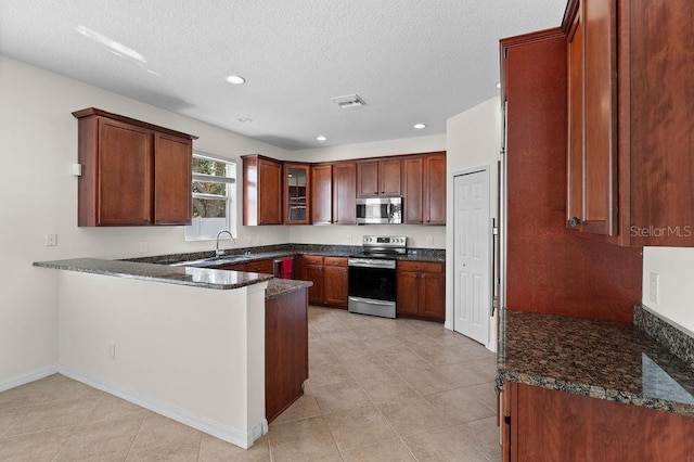 4429 67th St E, Bradenton, FL 34203 - kitchen with stainless steel appliances, a peninsula, a sink, dark stone countertops, and glass insert cabinets