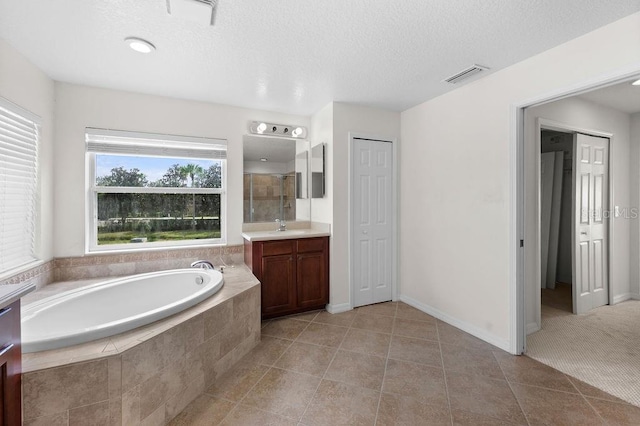 4429 67th St E, Bradenton, FL 34203 - full bath with vanity, a bath, tile patterned floors, a shower with shower door, and a textured ceiling