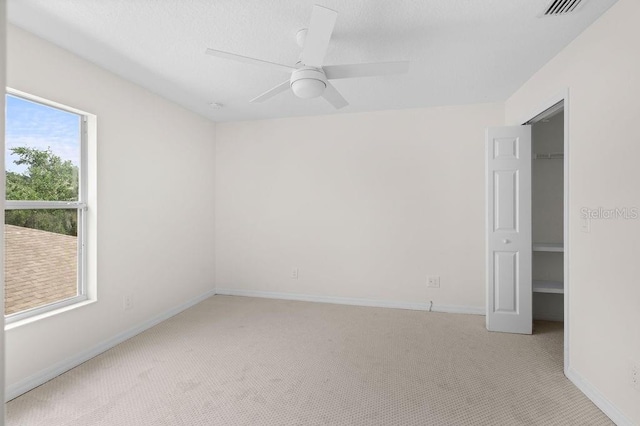 4429 67th St E, Bradenton, FL 34203 - unfurnished bedroom featuring light carpet, a spacious closet, baseboards, and a ceiling fan