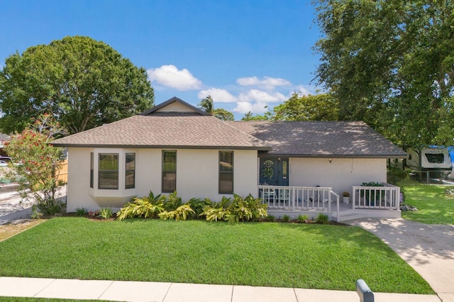 ranch-style home featuring a front lawn, stucco siding, and roof with shingles