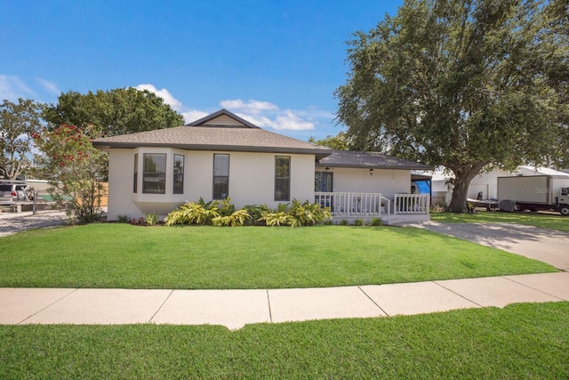 view of front of property featuring stucco siding, a front yard, and roof with shingles