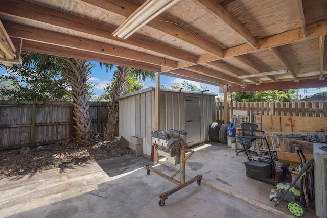 view of patio featuring a storage shed, a fenced backyard, and an outdoor structure