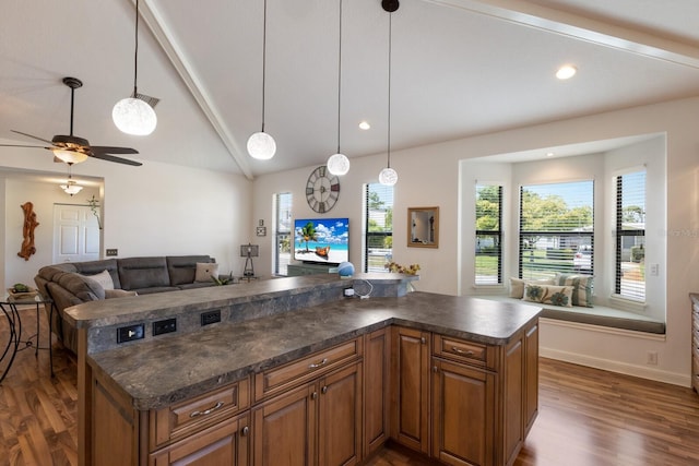 kitchen with brown cabinets, dark countertops, open floor plan, dark wood-style floors, and a kitchen island
