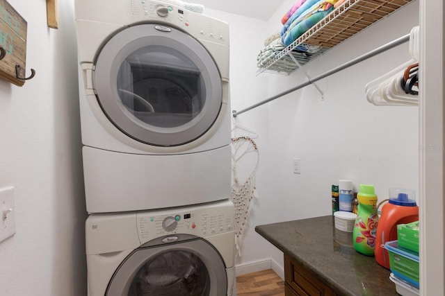 laundry room with stacked washer / dryer and light wood-style flooring