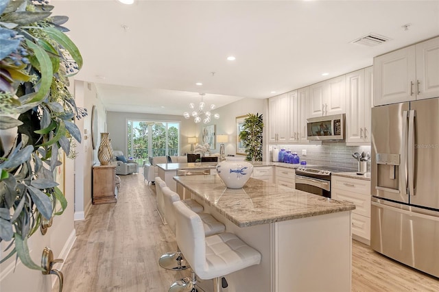 8735 Olde Hickory Ave Unit 8205, Sarasota, FL 34238 - kitchen featuring stainless steel appliances, light wood-type flooring, open floor plan, light stone countertops, and recessed lighting