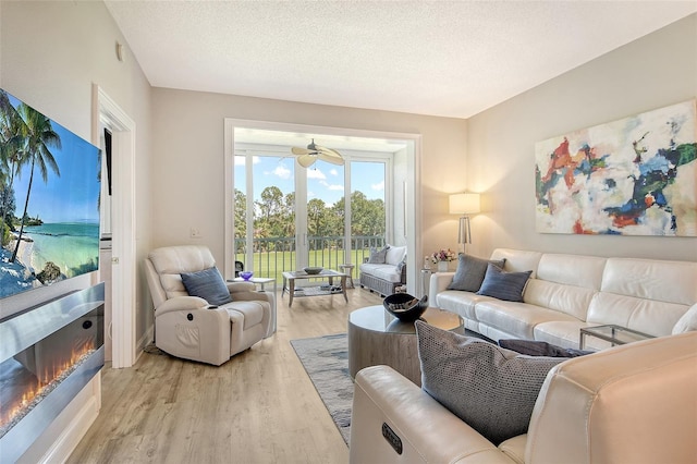 8735 Olde Hickory Ave Unit 8205, Sarasota, FL 34238 - living room featuring light wood finished floors, a glass covered fireplace, ceiling fan, and a textured ceiling