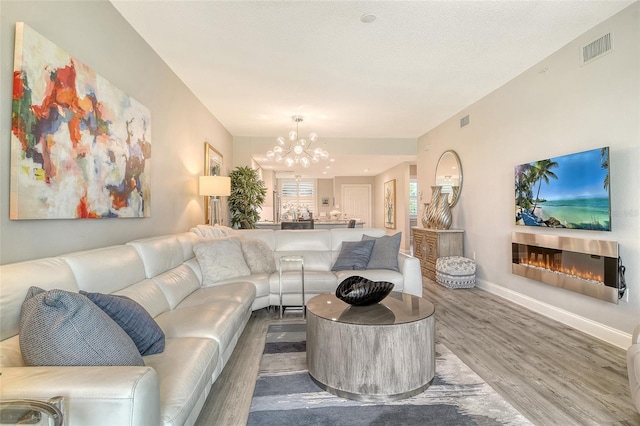8735 Olde Hickory Ave Unit 8205, Sarasota, FL 34238 - living area with wood finished floors, a chandelier, a glass covered fireplace, and baseboards