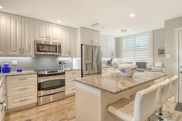 8735 Olde Hickory Ave Unit 8205, Sarasota, FL 34238 - kitchen featuring appliances with stainless steel finishes, light stone countertops, light wood-style floors, backsplash, and white cabinets