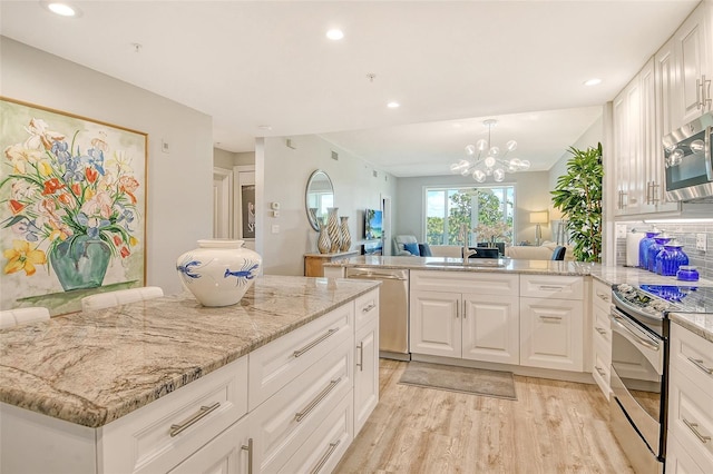 8735 Olde Hickory Ave Unit 8205, Sarasota, FL 34238 - kitchen featuring appliances with stainless steel finishes, a peninsula, open floor plan, light wood finished floors, and white cabinetry