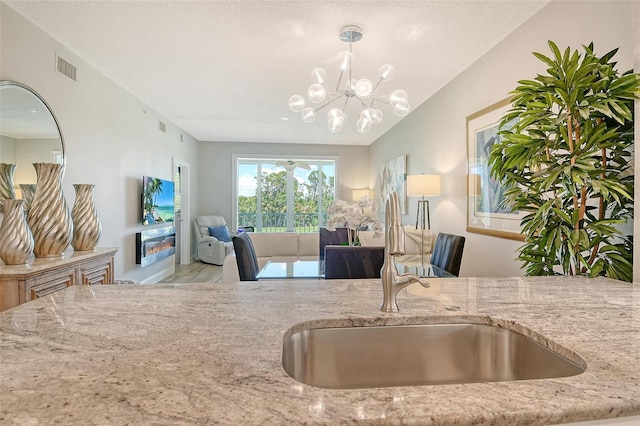 8735 Olde Hickory Ave Unit 8205, Sarasota, FL 34238 - kitchen with a sink, open floor plan, light stone countertops, a chandelier, and pendant lighting