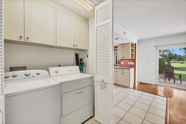 6701 12th Ave W, Bradenton, FL 34209 - washroom featuring cabinet space, washer and dryer, a textured ceiling, and light tile patterned floors