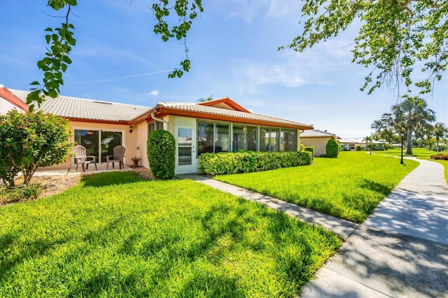6701 12th Ave W, Bradenton, FL 34209 - rear view of house featuring a tiled roof, a sunroom, a yard, a patio, and stucco siding