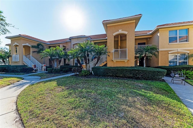 8422 Wethersfield Run Unit 103, Lakewood Ranch, FL 34202 - view of front of home with stucco siding, stairs, a tile roof, and a front lawn