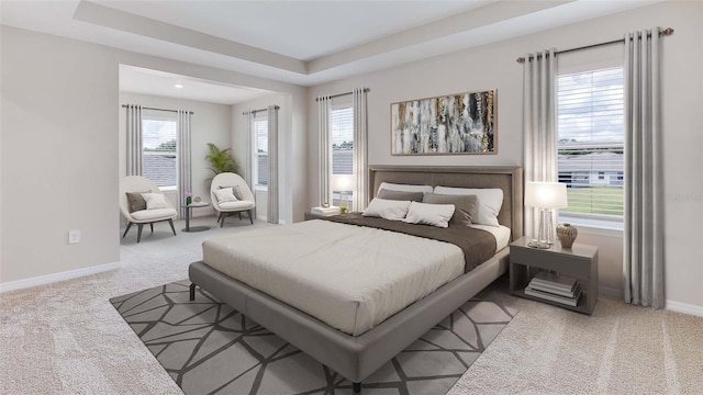 carpeted bedroom with baseboards and a raised ceiling