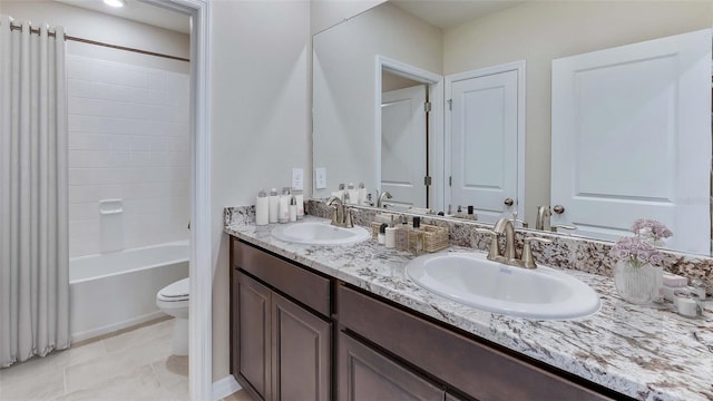 bathroom featuring toilet, double vanity, shower / bath combo with shower curtain, and tile patterned flooring