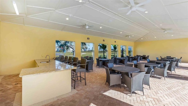 view of patio with a ceiling fan, an outdoor bar, and fence