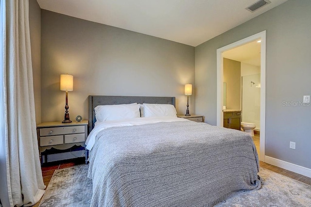 bedroom featuring wood finished floors, ensuite bath, and baseboards