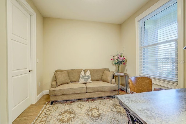 living area with plenty of natural light, light wood-style floors, and baseboards