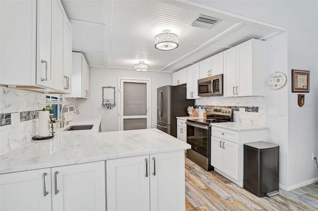 2127 Corfell St, Port Charlotte, FL 33948 - kitchen with stainless steel appliances, a sink, light wood finished floors, decorative backsplash, and white cabinetry