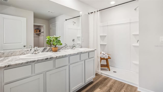 full bath with a shower with shower curtain, wood finished floors, and double vanity