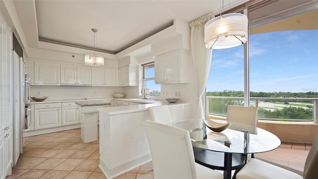 3060 Grand Bay Blvd Unit 182, Longboat Key, FL 34228 - kitchen featuring light tile patterned flooring, light countertops, white cabinets, a raised ceiling, and pendant lighting