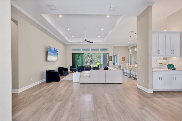 living area with a raised ceiling, light wood-type flooring, a ceiling fan, baseboards, and recessed lighting