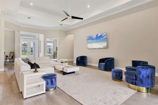 living area with wood finished floors, a raised ceiling, baseboards, ceiling fan, and french doors
