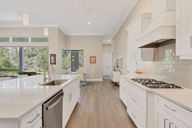 kitchen featuring a sink, stainless steel appliances, custom range hood, light countertops, and tasteful backsplash