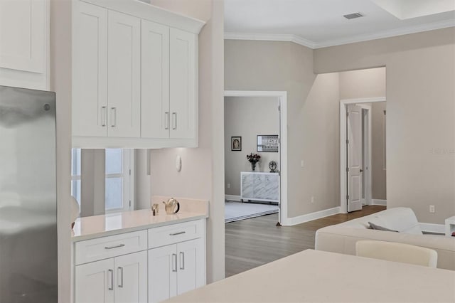 kitchen with stainless steel fridge, ornamental molding, dark wood-type flooring, white cabinetry, and baseboards