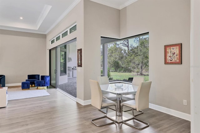dining space featuring ornamental molding, a high ceiling, wood finished floors, baseboards, and recessed lighting