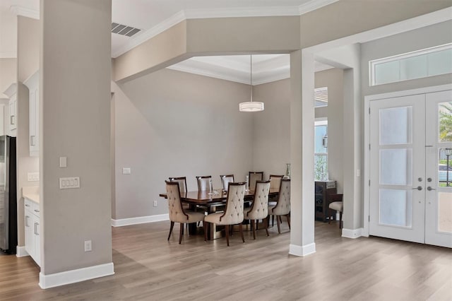dining area with light wood finished floors, ornamental molding, healthy amount of natural light, baseboards, and french doors