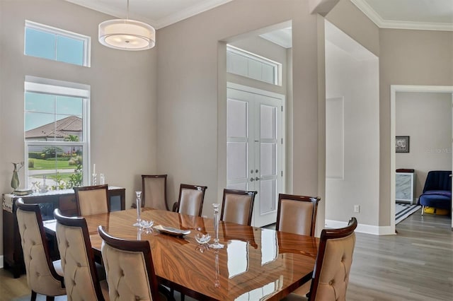 dining room with wood finished floors, ornamental molding, and baseboards