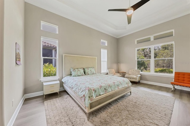 bedroom with crown molding, wood finished floors, baseboards, a towering ceiling, and a ceiling fan