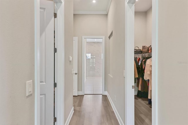 corridor with wood finished floors, baseboards, and crown molding